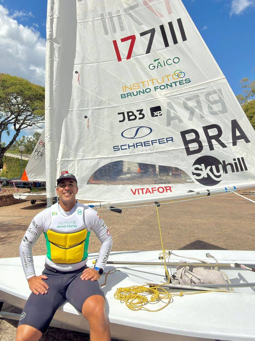 Bruno Fontes sentado no seu ILCA 7 com a marca do Instituto Bruno Fontes na vela e no uniforme